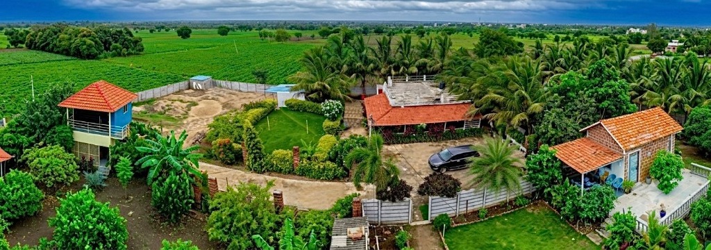 Aerial panoramic view of Divi's Eco Stay farmhouse property and lush green surroundings